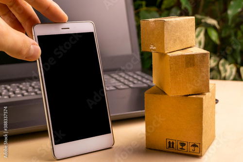 online shopping concept. little deliver boxes, smartphone, shopping bags, shopping bascket stand on laptop. copy space