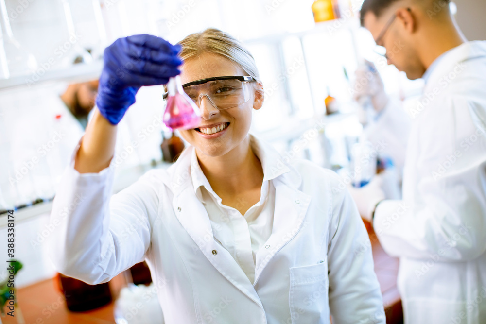 Young female scientist examining liquid in biochemical lab Young female scientist examining liquid in biochemical lab