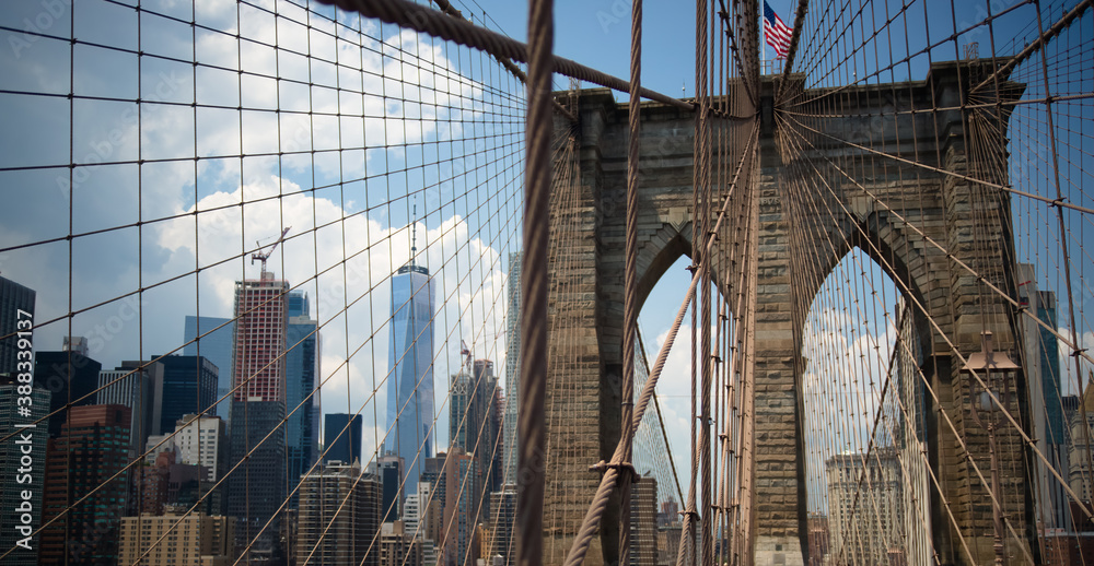 Fototapeta premium Brooklyn Bridge with modern buildings on the other side of the steel mesh.