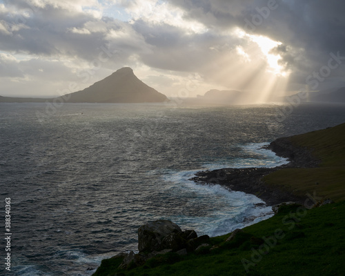 Hestfjörður fiord and island Koltur. Dramatic clouds and light shining through, strong wind. Faroe Islands. photo