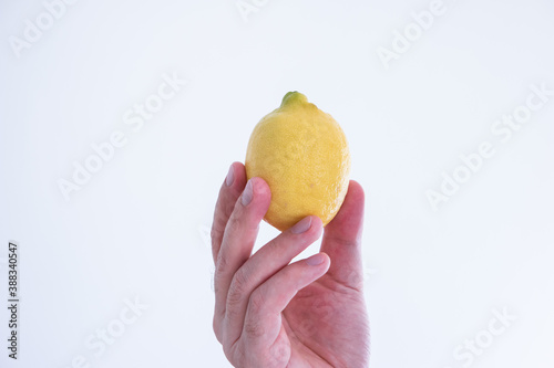 Whole yellow lemon held by Caucasian male hand close up shot isolated on white