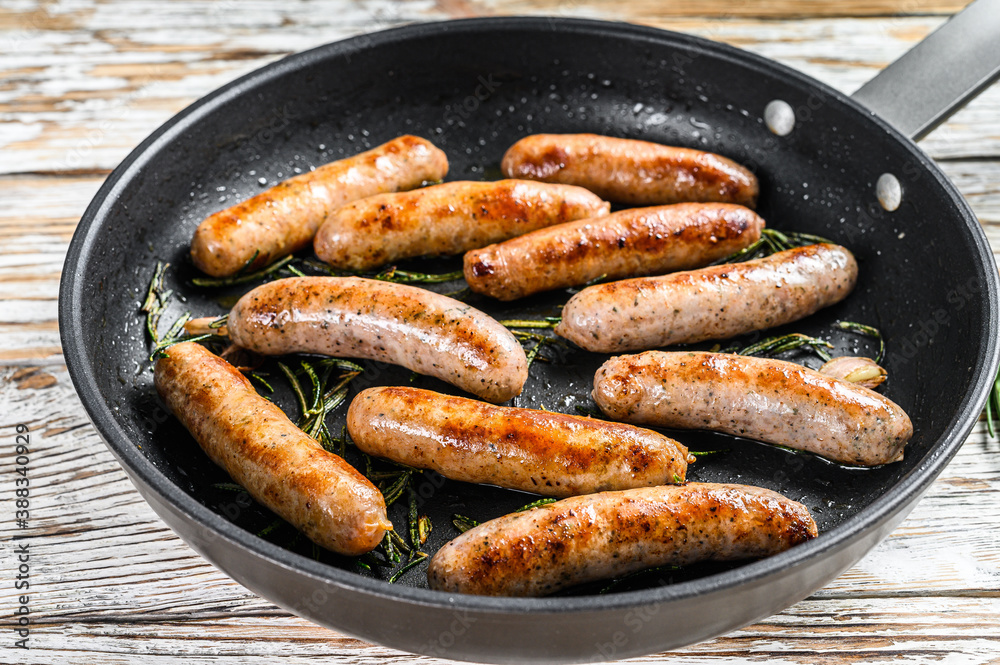 Homemade sausages fried in a pan, beef and pork meat. wooden background. Top view