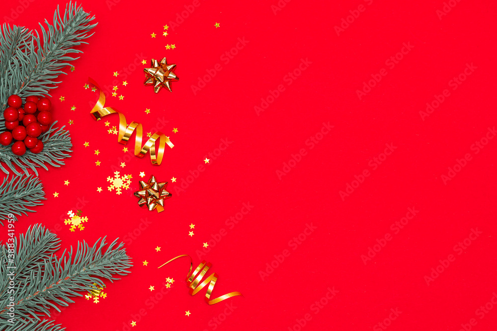 Fir tree branches and sparkling decorations on bright red background with copy space for your text. Christmas and New Year concept.