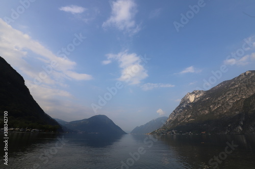 Clear water in Italy over a mountain range with still lake in foreground during the daytime in the late summer