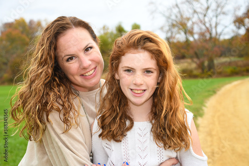 Mother and daughter pose for autumn portrait. 