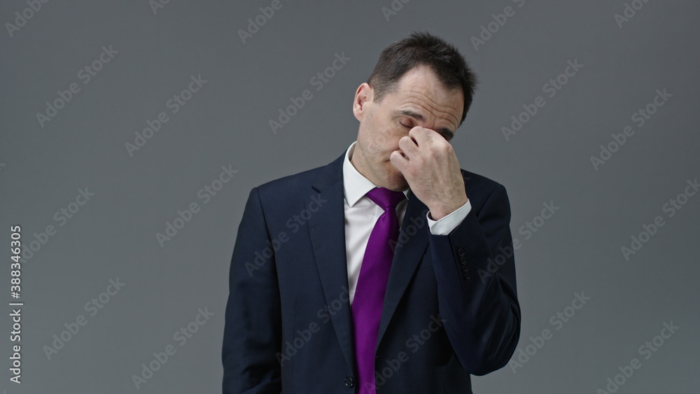 Overworked handsome middle aged office worker in formal clothes, tie feels tired, takes off glasses, holding hand on bridge of his nose on isolated grey background, people emotions concept Overworked handsome middle aged office worker in formal clothes, tie feels tired, takes off glasses, holding hand on bridge of his nose on isolated grey background, people emotions concept