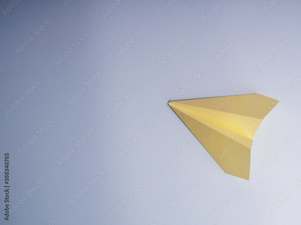 Flat lay of yellow paper plane and blank paper on pastel blue color background.Horizontal