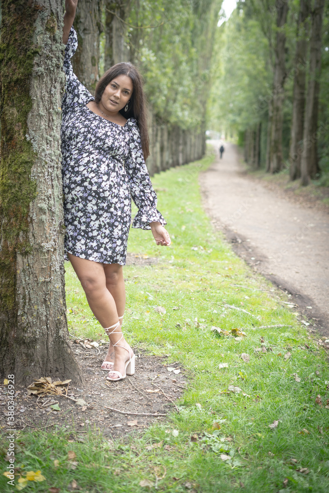 Mixed Race, Plus Sized Model Posing Against Tree In Park Mixed Race, Plus Sized Model Posing Against Tree In Park