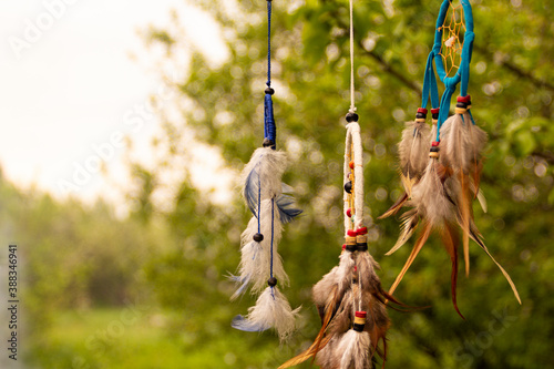 Dream catchers evolve in the wind, against a blurred green background of plants with copy space, symbol, tradition, signs. boho style