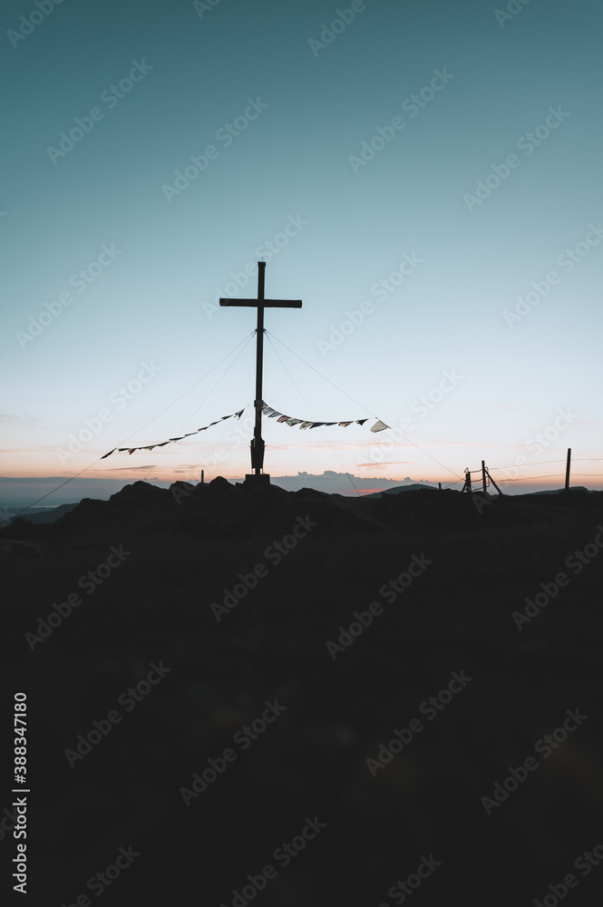 Obraz premium Gipfelkreuz am Riedberger Horn während dem Sonnenuntergang oder der blauen Stunde