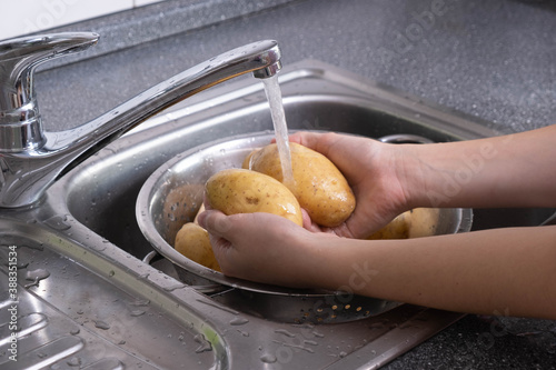 potatoes are washed under running waste water in the kitchen
