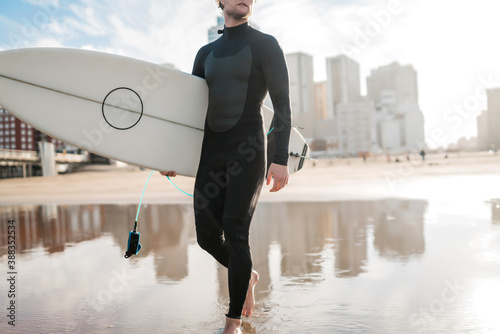 Surfer entering into the water with his surfboard.