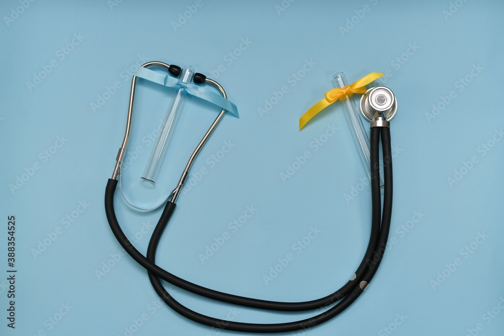 A medical stethoscope on a light blue background, with two test tubes, light blue and yellow. A medical stethoscope on a light blue background, with two test tubes, light blue and yellow.