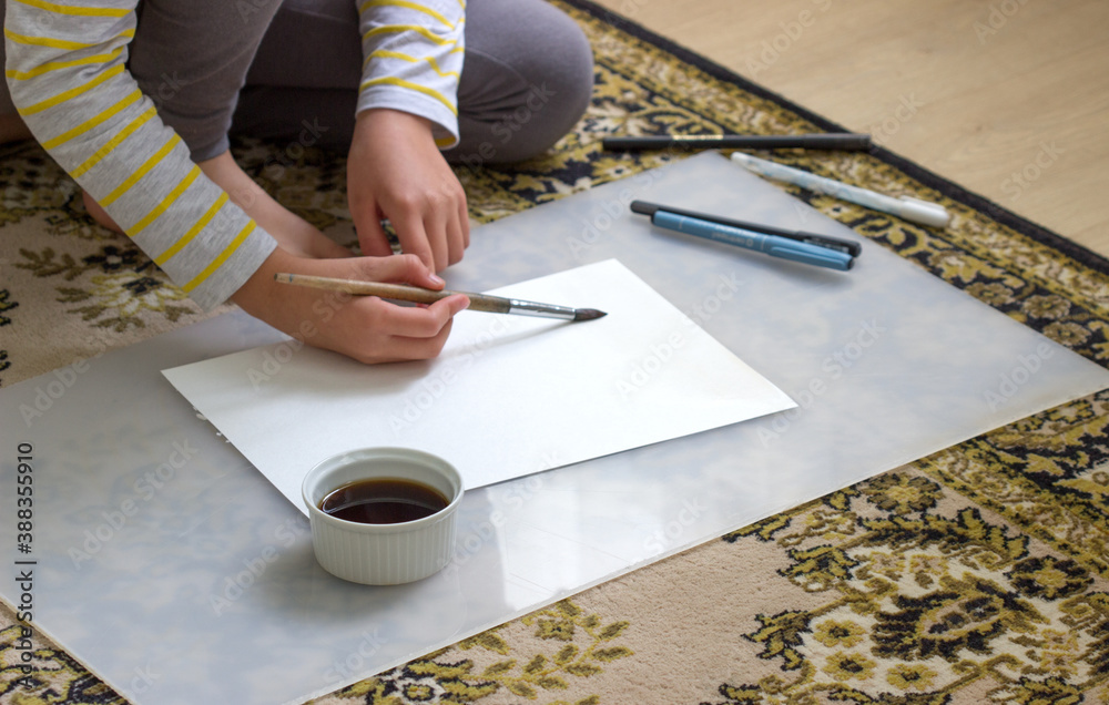 The girl at home draws with tea on watercolor paper.