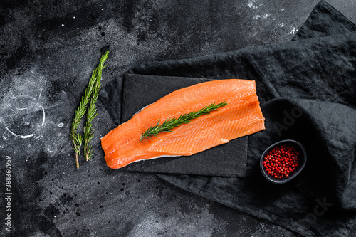 Raw salmon fillet with rosemary and pink pepper. Organic fish. Black background. Top view