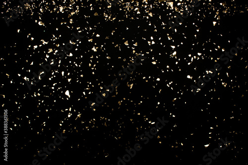 Festive luxury black background with holographic flying golden sparkles for your project. Holiday backdrop with copyspace. Birthday party, Christmas and New Year celebration concept