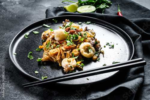 Asian stir fry Noodles with cuttlefish and vegetables. Black background. Top view