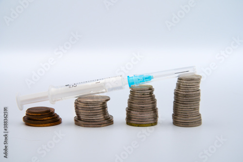 Wzrost pieniędzy i strzykawka z szczepionką. © Rafal