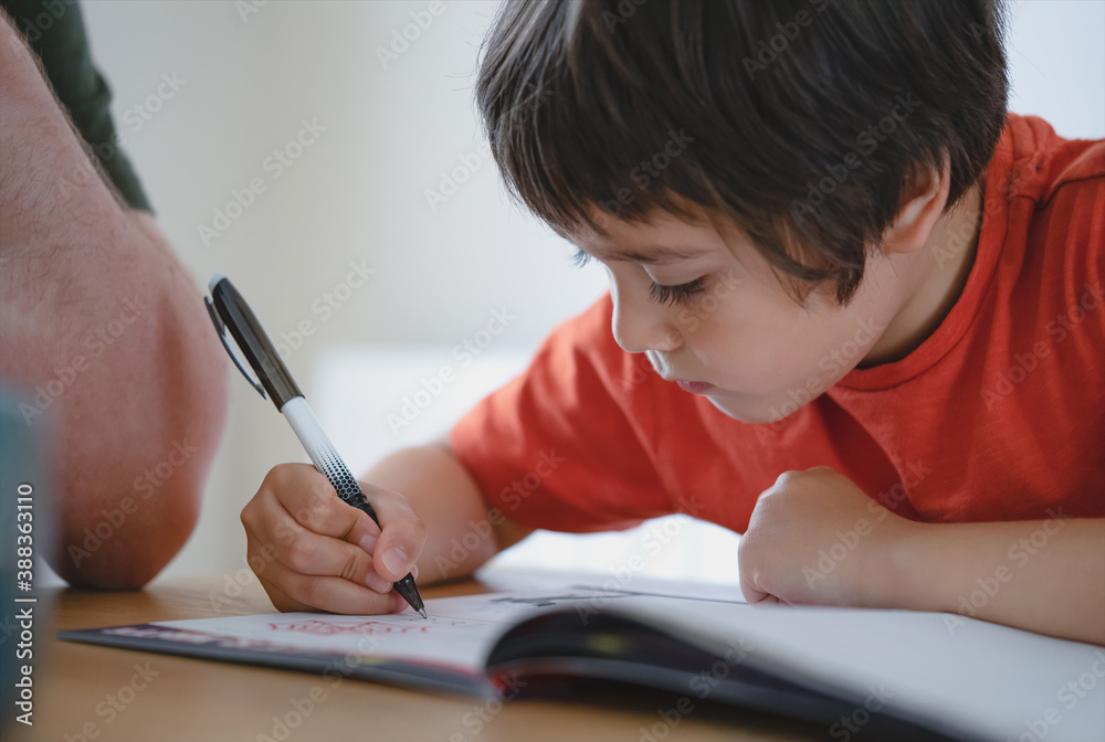 Cropped shot father helping his boy with homework, Dad and Son doing homework together, Teacher teaching little boy how to write. Man hand holding pen, Education concept Cropped shot father helping his boy with homework, Dad and Son doing homework together, Teacher teaching little boy how to write. Man hand holding pen, Education concept