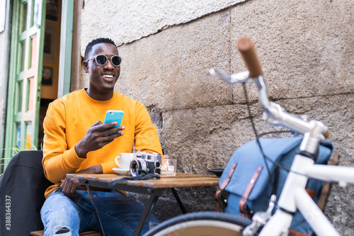 Black Tourist Man Using Cellphone Sitting in in a Cafe.