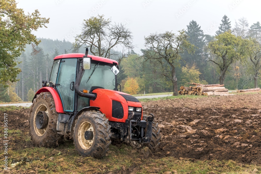 Red tractor on a muddy field. Agricultural work. Autumn foggy morning on the farm. Agriculture machinery. Red tractor on a muddy field. Agricultural work. Autumn foggy morning on the farm. Agriculture machinery.