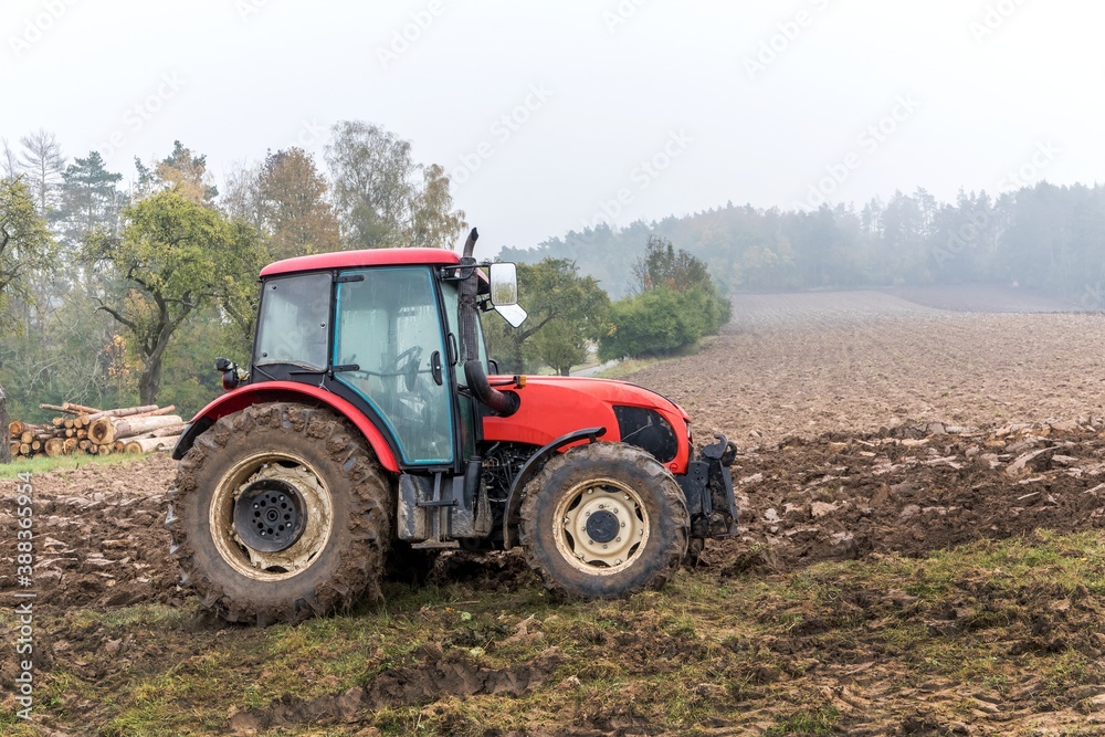 Red tractor on a muddy field. Agricultural work. Autumn foggy morning on the farm. Agriculture machinery. Red tractor on a muddy field. Agricultural work. Autumn foggy morning on the farm. Agriculture machinery.