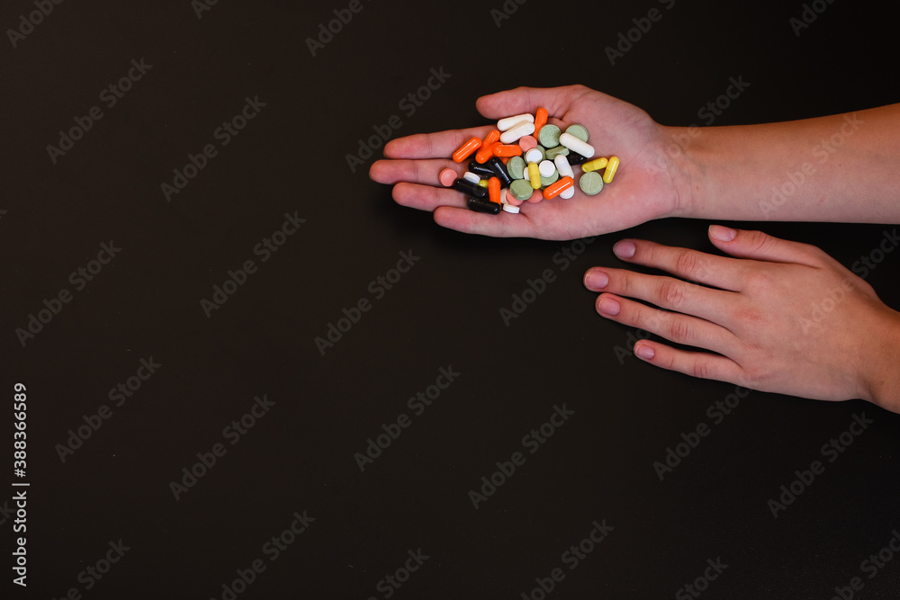 Hands with colorful pills. Place for an inscription. On a black background. Place for inscription. High quality photo