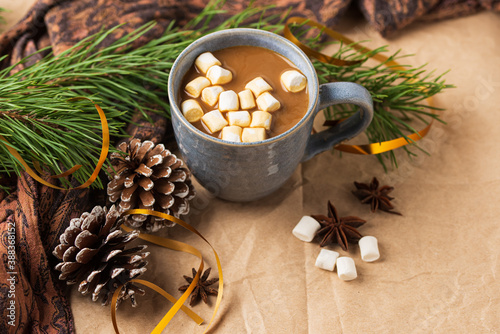 A Cup of coffee or cocoa with marshmallows with Christmas tree or New year decor. Winter still life with a warm drink, scarf, anise stars and cones