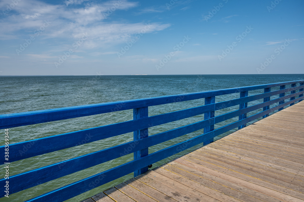 Pier from boards with blue fence against the sea and blue sky with clouds on a sunny day, copy space Pier from boards with blue fence against the sea and blue sky with clouds on a sunny day, copy space