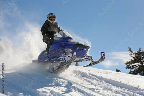 extreme snowmobile rider racing machine through powder in mountains photo