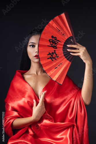 Fotografie, Obraz beautyful girl dressed as a geisha in a red kimono with a fan