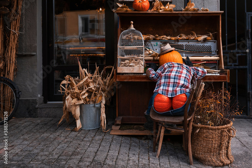 Pumpkin man playing old piano. Creative outdoor Halloween decor. Orange pumpkin scarecrow. Funny fall harvest festival decoration. photo