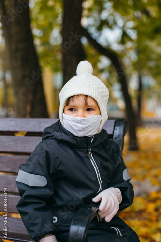 small child of a girl 3 years old, on the street in a hat and a medical mask during the coronavirus pandemic in russia 