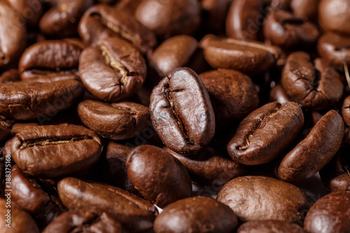 Freshly roasted coffee beans background.Dark roasted coffee beans with scoop on wooden background.