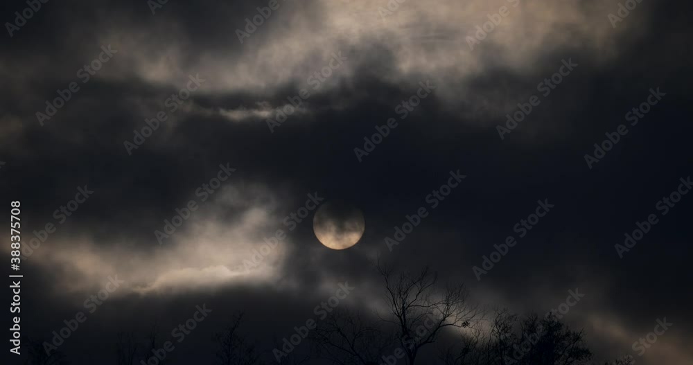 Sun Behind Dark Gray Clouds Moving Fast. Round Solar Disk. Strong Wind Weather Climate Evening Dusk Grey Sky Sun Behind Dark Gray Clouds Moving Fast. Round Solar Disk. Strong Wind Weather Climate Evening Dusk Grey Sky