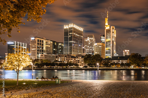 city skyline at night, people walk on the main river