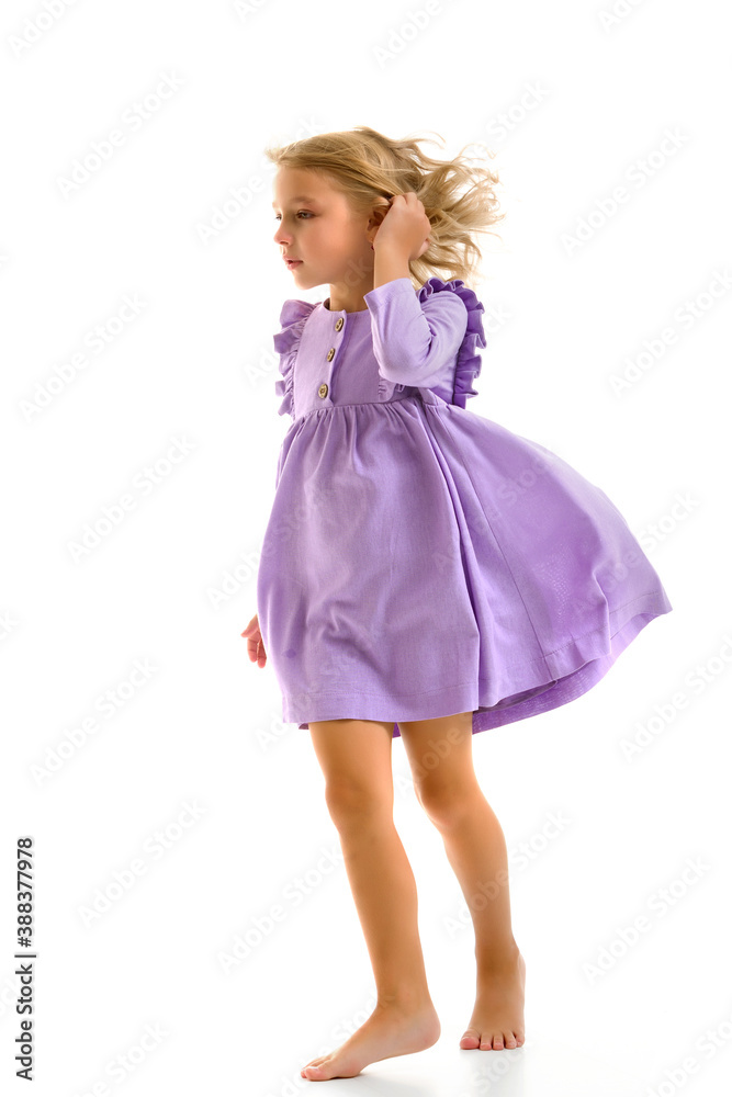 A beautiful little girl stands in the wind, her hair and clothes are developing greatly. The concept of style and fashion.