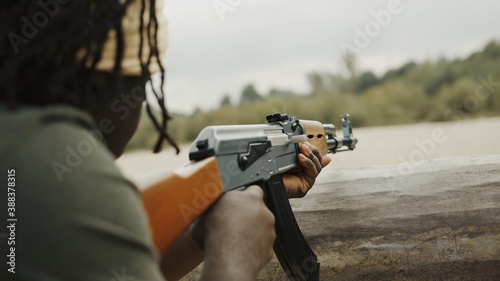 Close up, unrecognizable black man with head covering pulling triger of AK-47 machine gun. Concept of terrorism. High quality photo photo