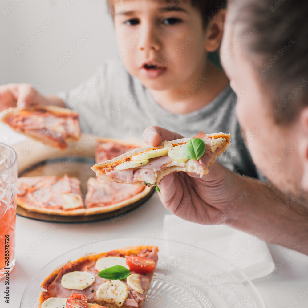 Kid and family eating homemade pizza. Italian cuisine recipe baked at home with natural, healthy ingredients: zucchini, prosciutto, cherry tomatoes, mozzarella and basil. Lifestyle. Selective focus. 
