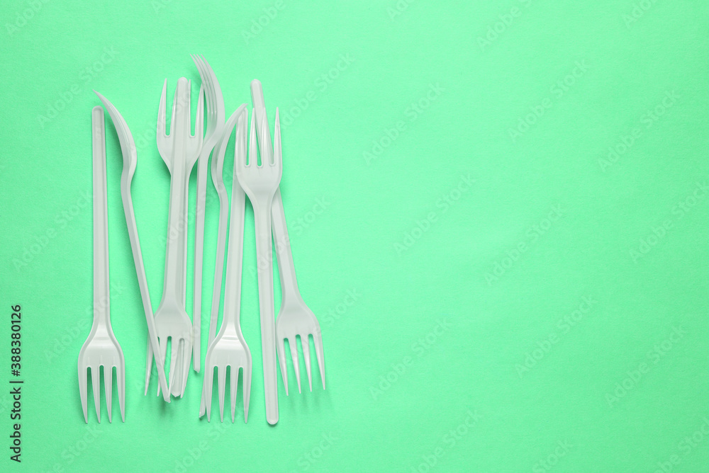 Plastic forks on a green background with a copy of the space. Disposable food appliances Plastic forks on a green background with a copy of the space. Disposable food appliances