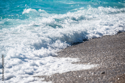 Fototapeta Naklejka Na Ścianę i Meble -  Refreshing sea wave with foam on pebble beach