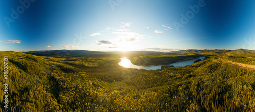 Beautiful View of Scenic Valley from Above alongside Winding River, Forest and Mountains at Sunset. Aerial Drone Shot. Taken near Klondike Highway, Yukon, Canada.