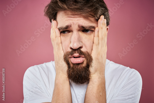 bearded man in white t-shirt emotions displeased facial expression studio pink background