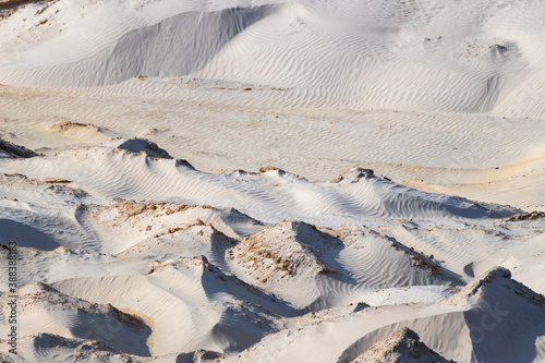 White sand dunes desert curves terrain. Light and shadow smooth rippled pattern of quarry sand