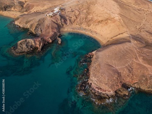 Aerial view of the jagged shores and beaches of Lanzarote, Spain, Canary. Roads and dirt paths. Walking routes to explore the island. Bathers on the beach. Atlantic Ocean. Papagayo
