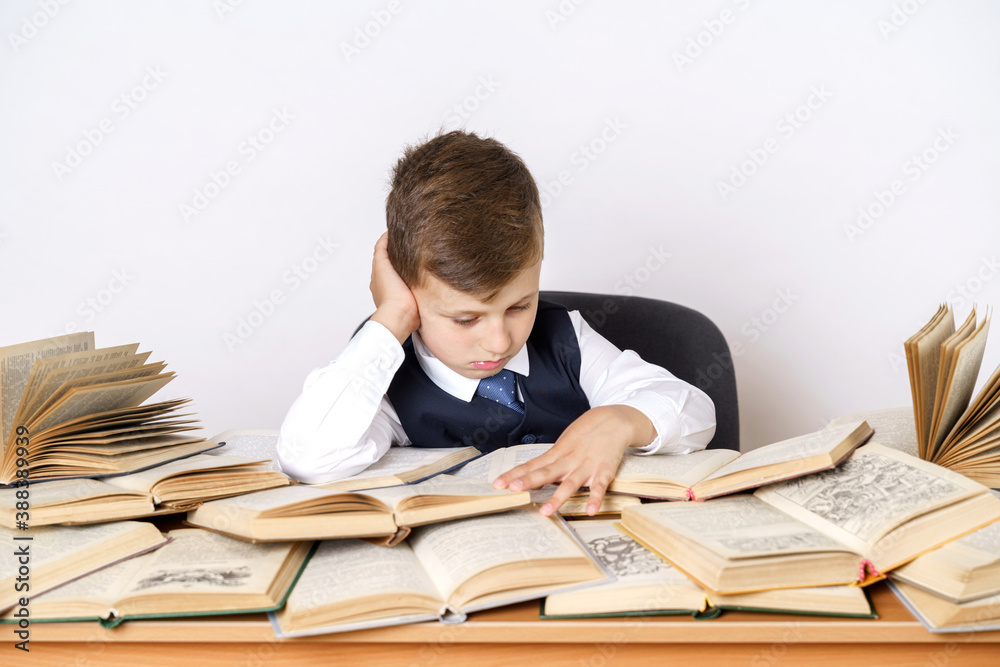 The student does homework, reads a book. There are many open books on the table. The student does homework, reads a book. There are many open books on the table.