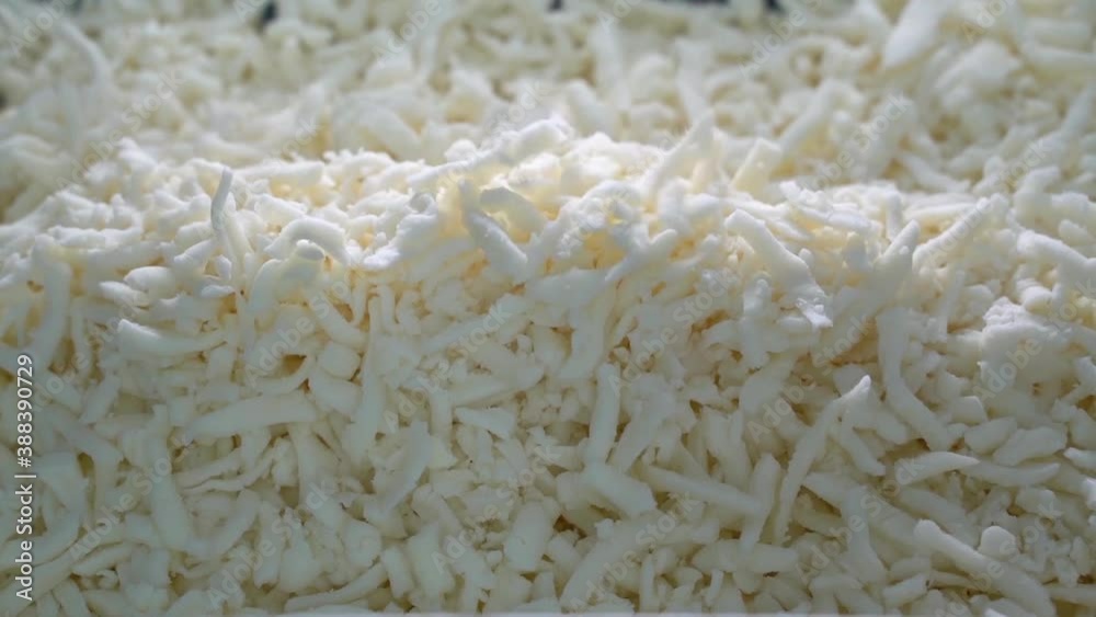 grated pizza mozzarella cheese falls in a plate from top. grated pizza mozzarella cheese falls in a plate from top.