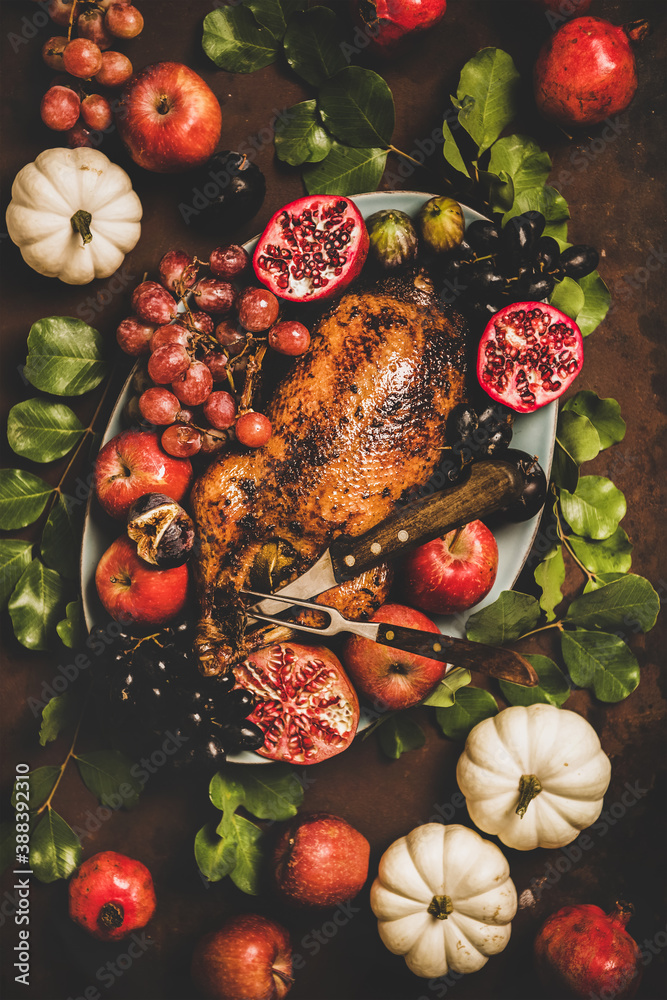 Autumn Thanksgiving, Friendsgiving, family party gathering celebration dinner. Flat-lay of Fall table with roasted duck in seasonal fruits decorated with pumpkins and leaves over rusty background