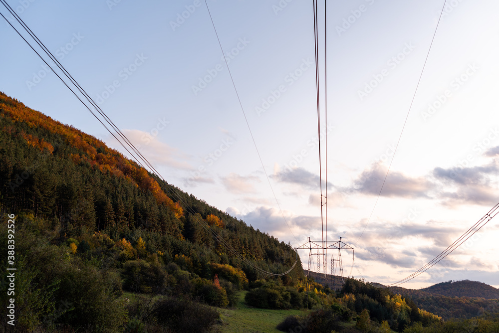 Autumn sunset orange green vibrant landscape rural power lines clouds blue sky hillside forest trees beautiful bulgaria