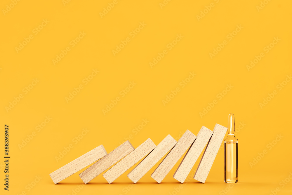 falling wooden blocks are stopped by an ampoule with vaccine. vaccination concept falling wooden blocks are stopped by an ampoule with vaccine. vaccination concept